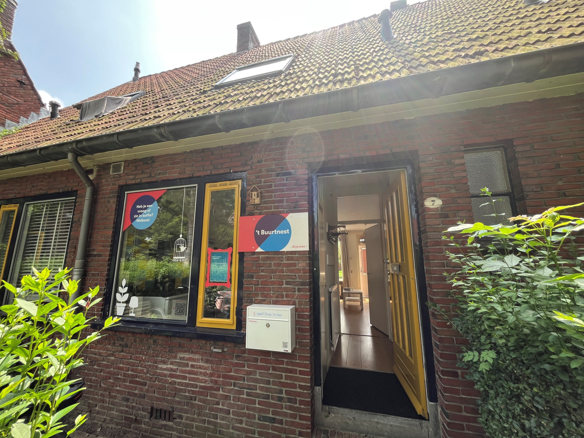 Een huis met een openstaande voordeur en bordjes bij het raam.