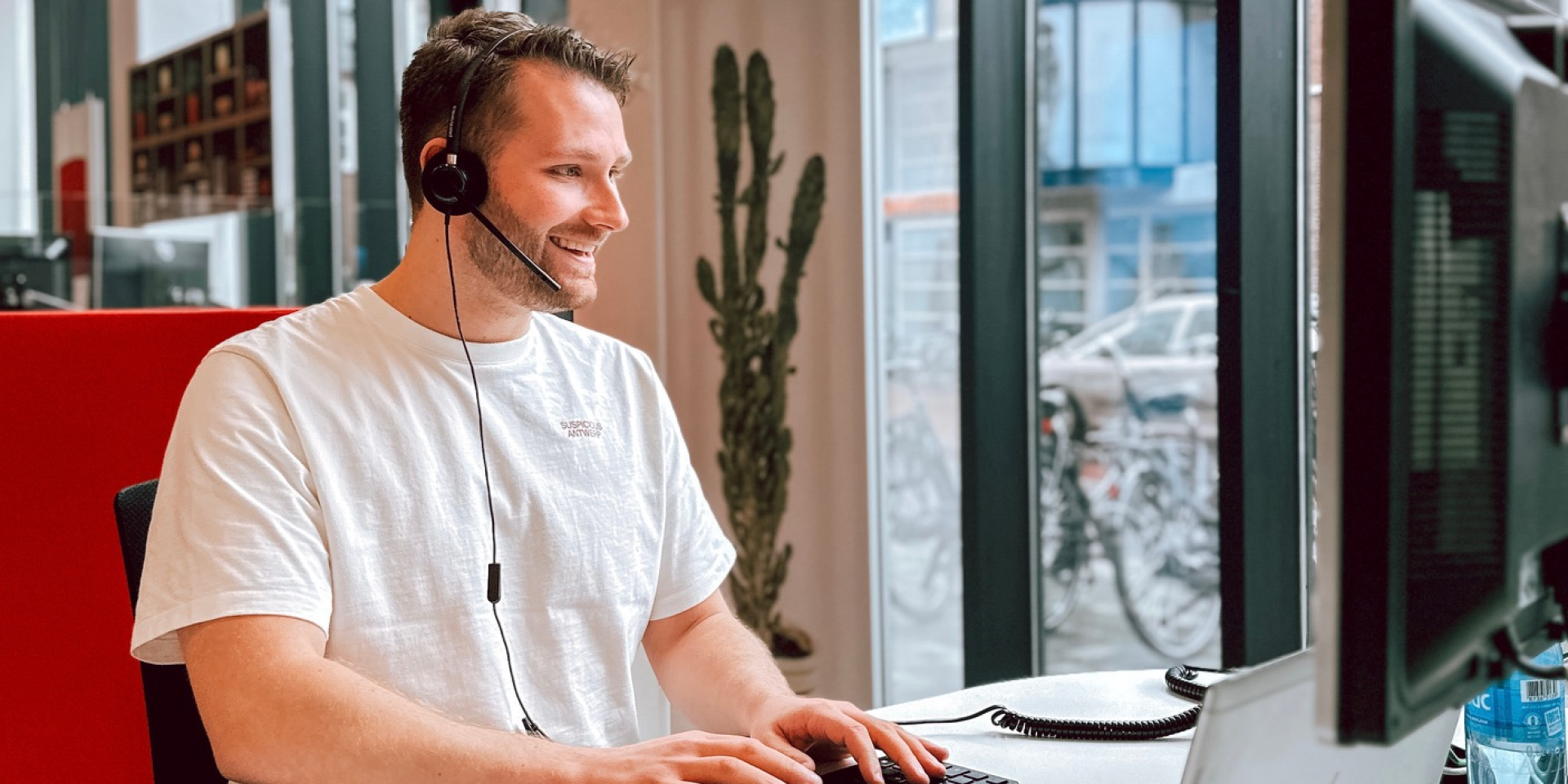 Man met een headset werkt aan een computer in een modern kantoor.