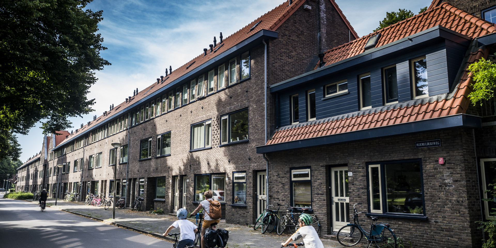 Fietsers rijden langs traditioneel rijtjeshuis met rode daken.